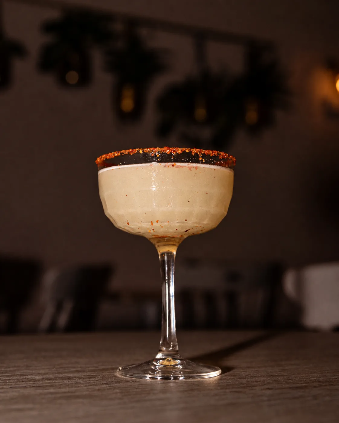 A cocktail in a stemmed glass against a dark background